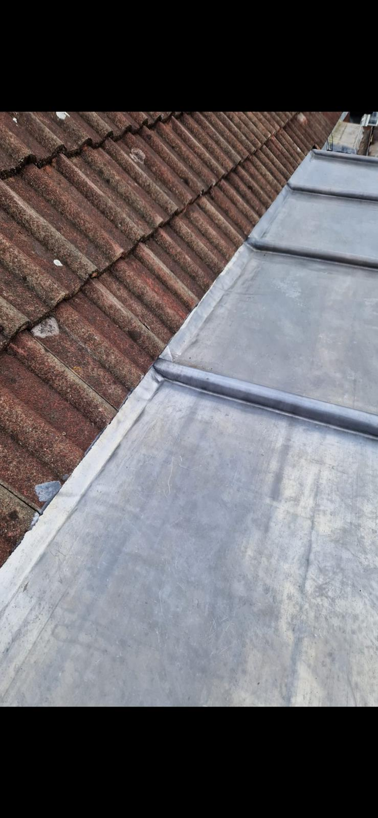 Close-up of lead flashing detail beside tiled roofing